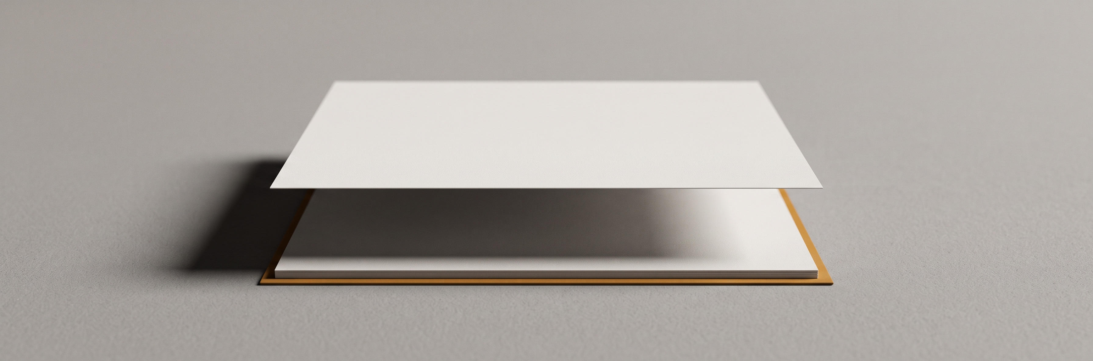 Two identical sheets of paper on a dark surface, one lying flat and one lifted a few centimetres above it.