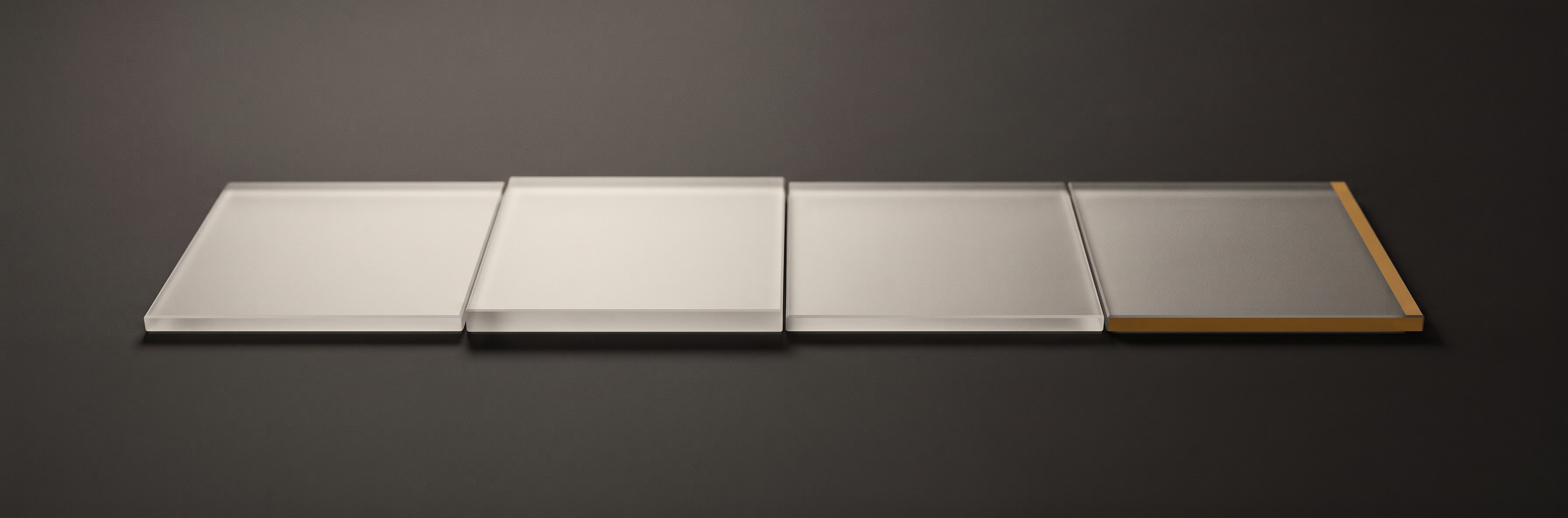 Four rectangular panes of frosted glass laid end to end in a single row on a dark surface.